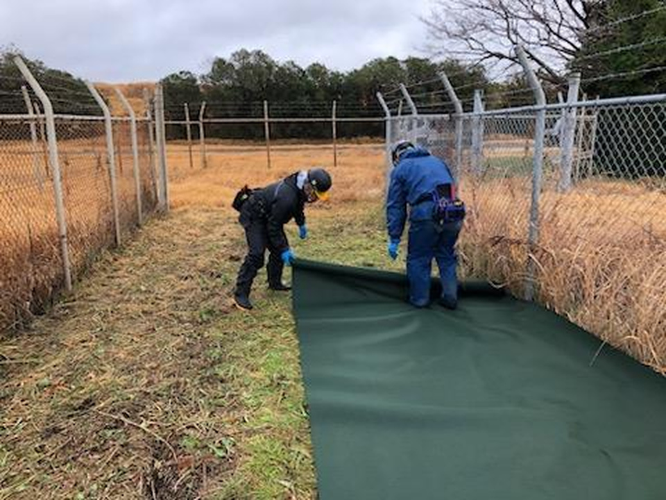 フェンス沿いに防草シートを敷設している作業